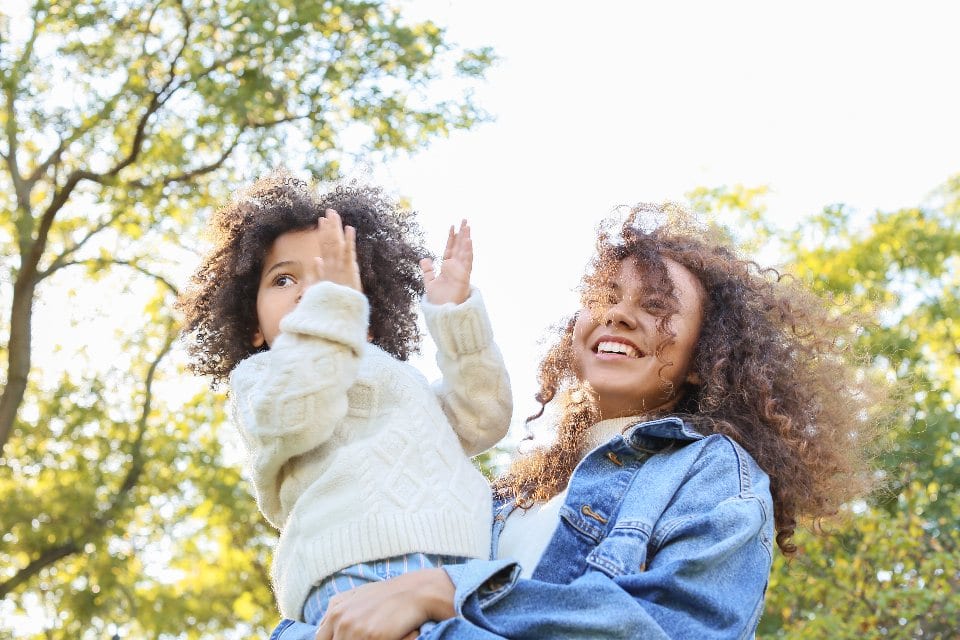 A parent and child sharing a joyful moment outdoors
